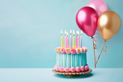 Beautiful birthday cake with piped buttercream flowers, birthday candles and pink and gold birthday balloons