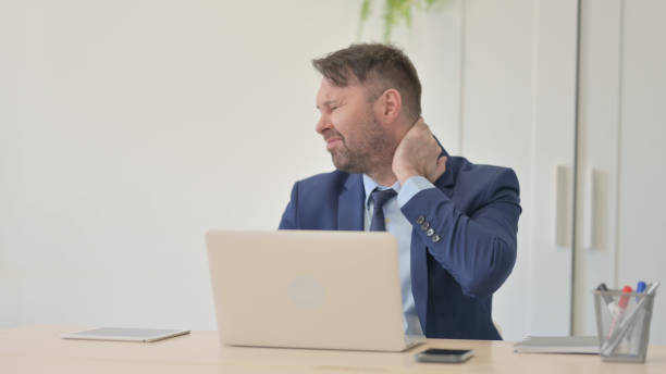 businessman with neck pain working on laptop - 30469 imagens e fotografias de stock