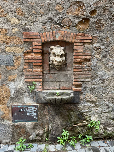 istock Gargoyle figure notched into stone wall with fountain 1493506126