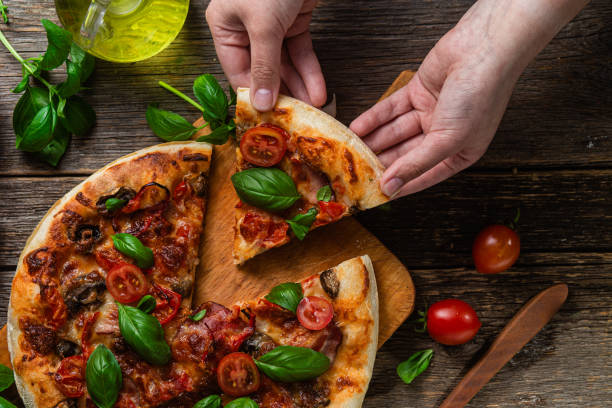 istock Appetizing pizza. Pizza with ham,mushrooms and tomatoes on a wooden background 1493508143