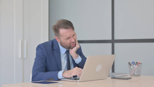 istock Businessman having Toothache while Working on Laptop, infection 1493508403