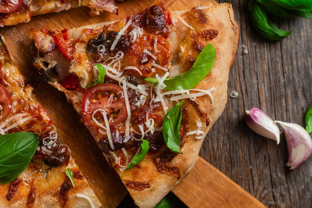 istock Appetizing pizza. Pizza with ham,mushrooms and tomatoes on a wooden background 1493508536