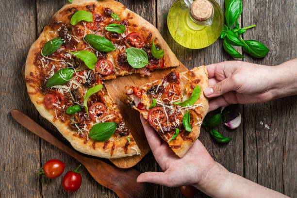 istock Appetizing pizza. Pizza with ham,mushrooms and tomatoes on a wooden background 1493509797