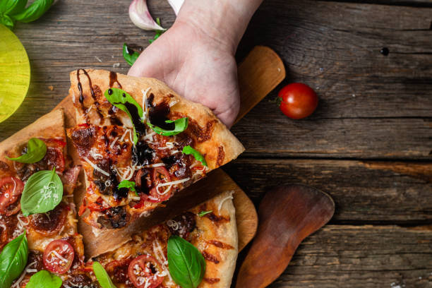 istock Appetizing pizza. Pizza with ham,mushrooms and tomatoes on a wooden background 1493509836