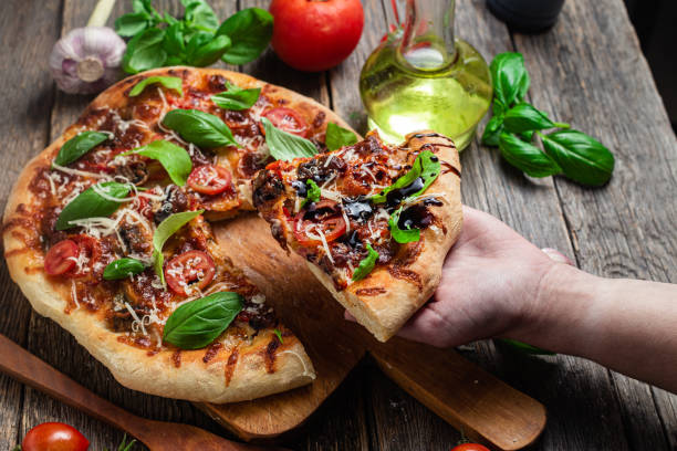 istock Appetizing pizza. Pizza with ham,mushrooms and tomatoes on a wooden background 1493510026