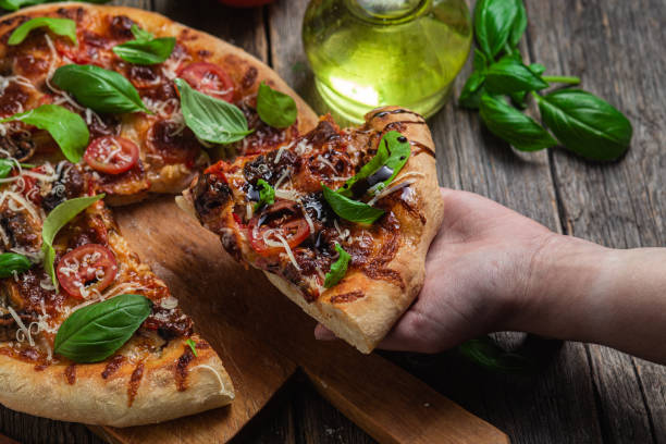 istock Appetizing pizza. Pizza with ham,mushrooms and tomatoes on a wooden background 1493510028