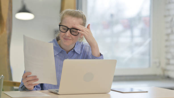 istock Young Woman Shocked by Loss on Laptop and Documents, Paperwork 1493514269