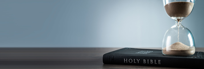 Hourglass and bible on the table