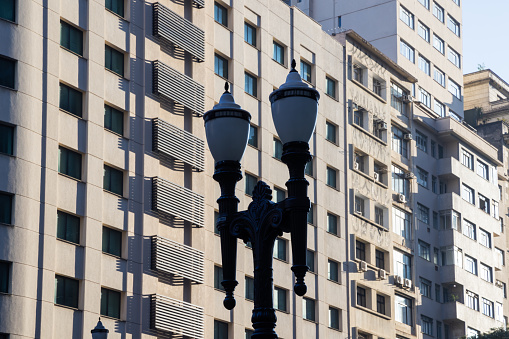 Close-up of a pole of vintage street lights against the blue glass exterior of a modern office building.