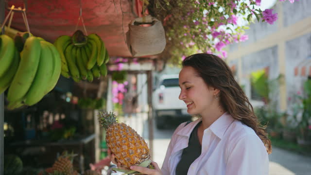 Woman choosing pineapple in grocery store in Thailand