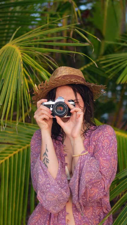 Woman making memories with vintage camera during beach vacation