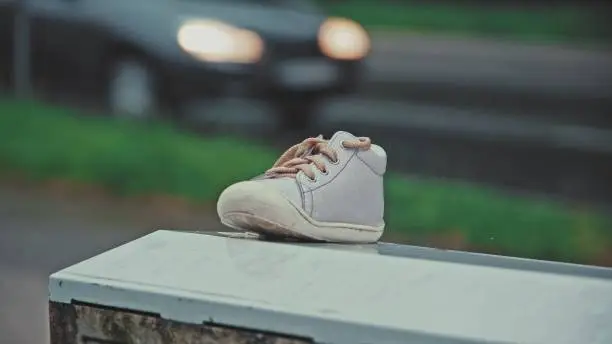 Lost Baby Shoe Left Outdoor On Metal Box on Cold Rainy Day
