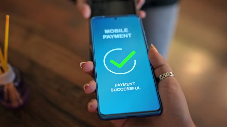 Young group of friends relaxing in a café, drinking juice and coffee. Young woman paying the bill via contactless channel by mobile banking application. Close-up.
