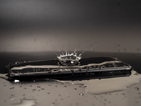 Water has been spilled on the Smartphone. The smartphone fell into the water. Wet smartphone on a black background.
