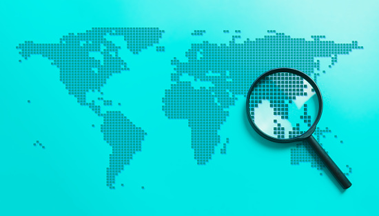 Magnify glass zooming the pixelated country in the world map on blue background. Geology and worldwide concept.