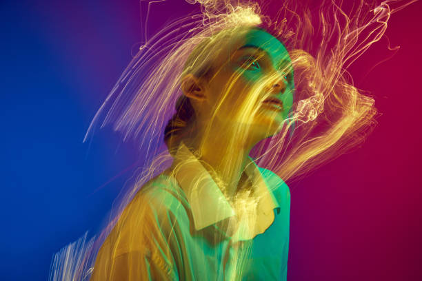 istock Portrait of young girl posing over gradient blue pink studio background with neon lights effect. Creative vision 1493526708