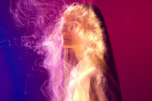 Burning art. Young tender girl posing with neon colored light reflection on body against gradient purple red background. Concept of art, modern style, cyberpunk, futurism and creativity