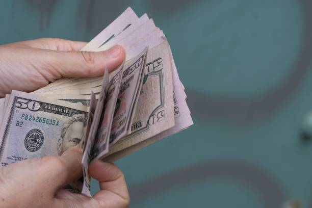 istock a person holding cash that they have folded over on their hand 1493527100