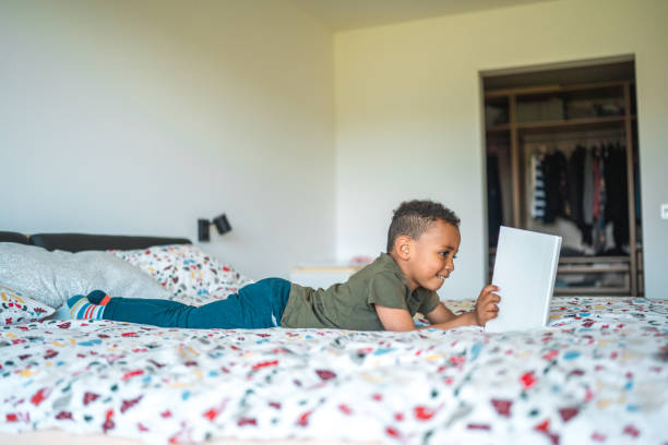 istock Adorable Mixed Race Boy Lying On The Bed Reading 1493527426