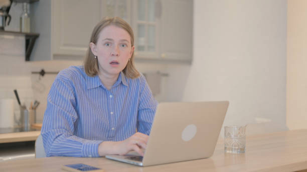 istock Shocked Young Woman Looking at Camera while Working on Laptop 1493533159