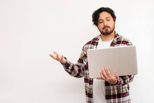 istock Person hispanic holding laptop with a hand while making confusion gesture in white background and copy space 1493533788