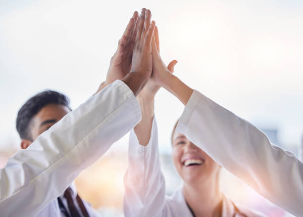 Doctor, group high five and teamwork with hands, celebration and motivation in hospital for healthcare. Man, woman and medic team building with support, solidarity and diversity in clinic for goal