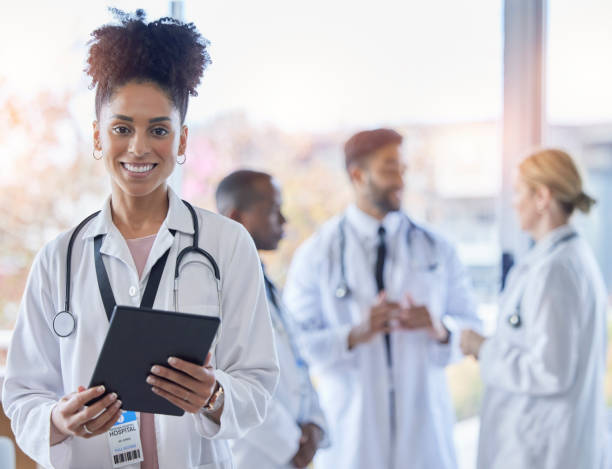 Black woman, doctor portrait and tablet with medical team in hospital ready for healthcare work. Wellness, health and medic employee in a clinic feeling happiness and success with blurred background stock photo