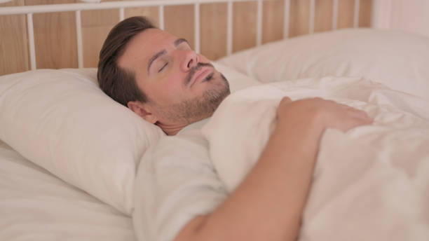 istock Tired Young Man Sleeping in Bed at Home 1493535494