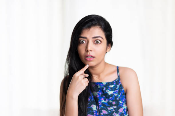 Shocked young woman thinking on white.