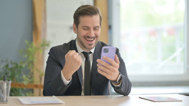 istock Businessman Celebrating Success on Smartphone 1493537808