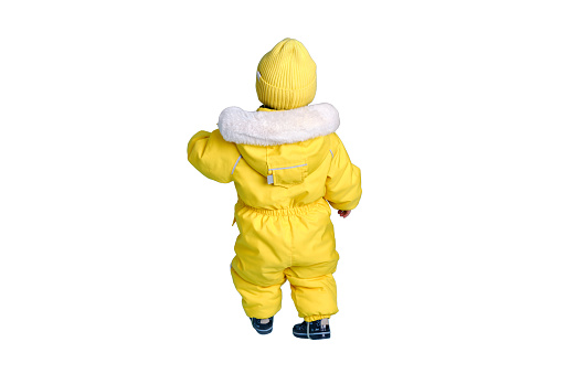 Happy toddler baby in winter clothes snowsuit isolated on a white background. A child in a warm yellow jumpsuit with a hood. Kid aged one year five months
