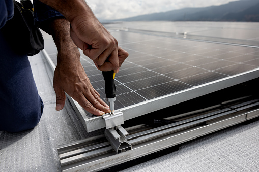 Power engineer installing solar panels on a rooftop