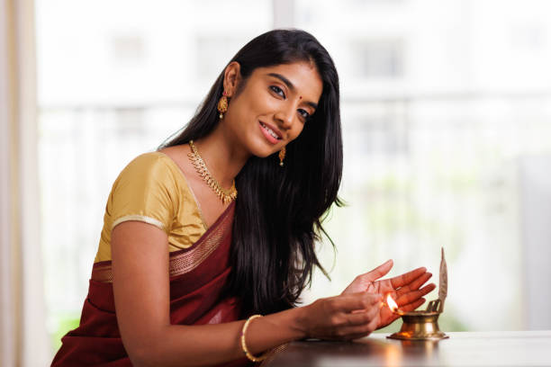 Beautiful Indian young women lightening deepa Beautiful Indian young women lightening deepa on Diwali day at home. tamil temple stock pictures, royalty-free photos & images