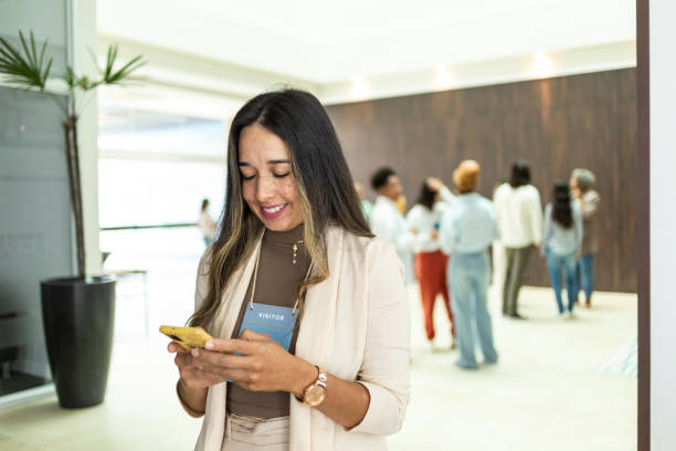 istock Smiling latin woman using cell phone in building lobby 1493548992