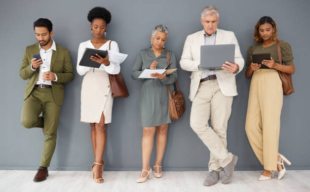 istock Office wall, row and business people with technology for networking, internet and job application. Recruitment, hiring line and group of workers on tablet, laptop and phone for interview opportunity 1493549151