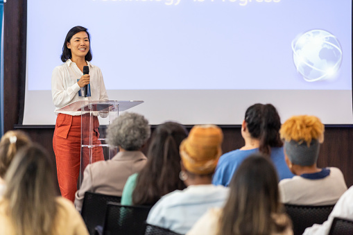 Asian woman giving lecture to business audience