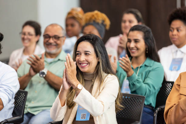 istock Latin woman in foreground clapping in crowded auditorium 1493555644