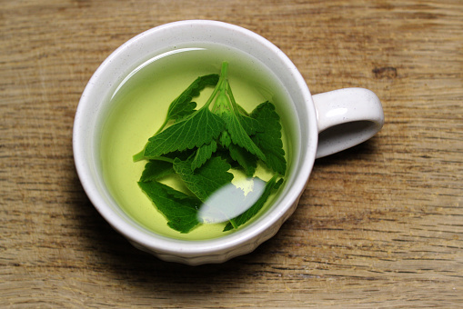 Tea Cup With Freshly Brewed Herbal Tea On Wooden Board Closeup Stock Photo