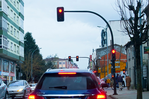 Driving at dusk, stop sign, red traffic lights, rear view of car waiting, tail lights. Galicia, Spain.