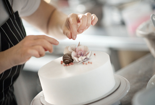 Closeup of an unrecognizable woman putting some finishing touches on a birthday cake.
