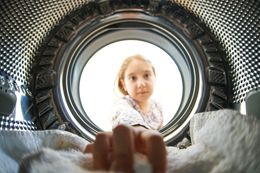 Little Girl Doing Laundry Reaching Inside Washing Machine