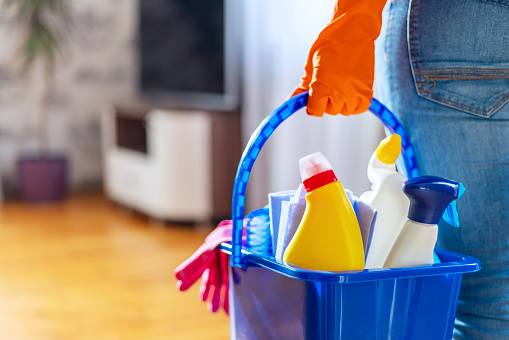 Woman in rubber gloves with bucket of cleaning supplies ready to clean up her apartment. Housewife has many household chores, domestic work and professional cleaning service. Low depth of field