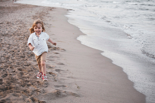 Happy little boy running on the beach.
