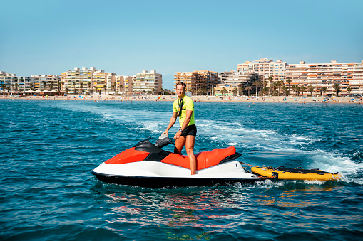 Young lifeguard guy on a jet ski in the Mediterranean sea in Water Rescue operation. Copy space