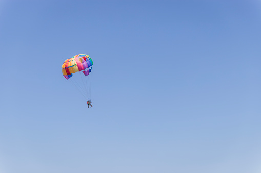 Two person flying on parachute over the ocean