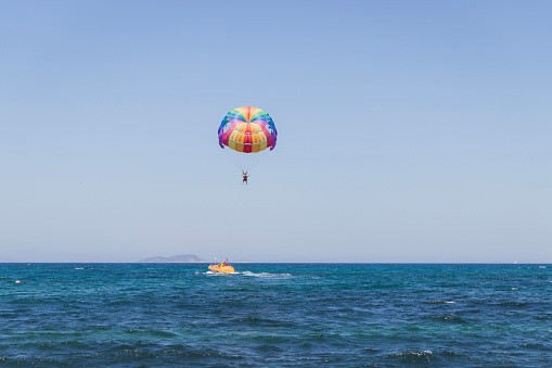 A person flying on parachute over the ocean