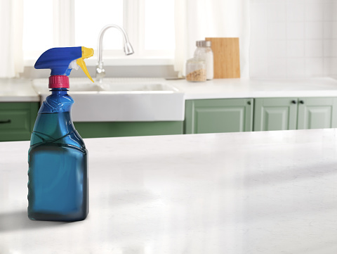 Cleaning spray bottle in a kitchen with a marble counter top and sink in the background