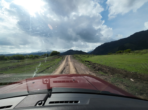 Car is driving on dirt mountain road. Car point of view