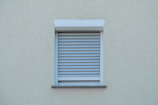 closed outdoor blind on a window on a white wall