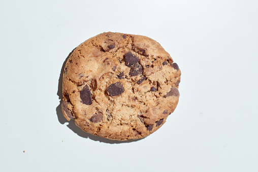 Fresh baked dark chocolate chip cookies on clear white photographed with hard light, a sweet favorite snack
